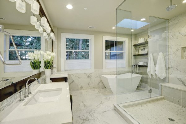 Image of an amazing white and gray marble master bathroom in Tega Cay, featuring a large glass walk-in shower, freestanding tub, and skylights on the ceiling.