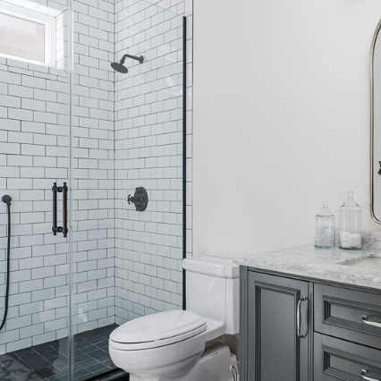 The image displays a contemporary bathroom in Fort Mill, featuring a glass-enclosed shower with white subway tile. The white subway tiles are arranged in a straight horizontal pattern, creating a clean and classic look. The glass enclosure adds a modern touch to the space and creates a sense of openness and transparency. The overall design is sleek and minimalist, with neutral tones and minimalist fixtures that create a sense of tranquility and serenity.