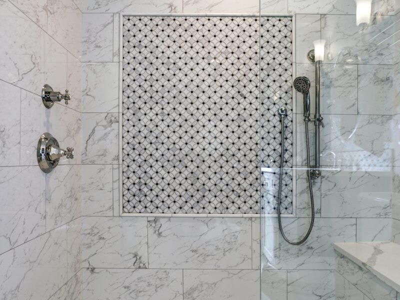 Tiled shower with Carrara marble surround and mosaic accent after tile installation in Fort Mill, SC.